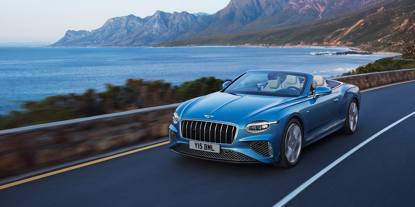 Bentley Budapest New Bentley Continental GTC Azure convertible in Light Windsor blue paint with 22 inch Azure wheels and chrome grill, driving dynamically by the sea