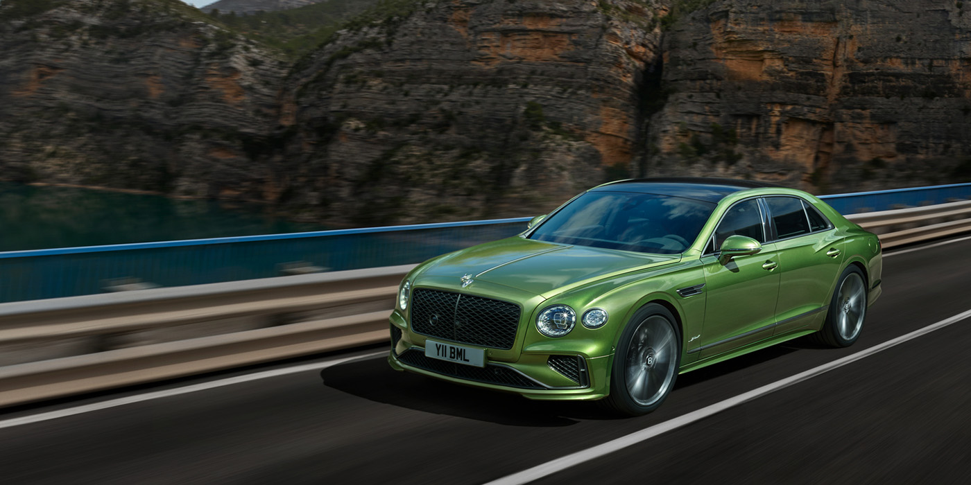 Bentley Budapest Bentley New Flying Spur Speed v8 hybrid sedan driving dynamically on a mountain road in Tourmaline Green paint