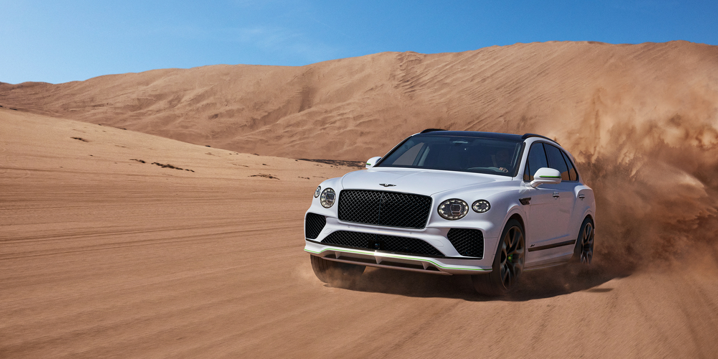 Bentley Budapest Bentley Bentayga Speed SUV front three quarter in Snow Quarts Pearlescent by Mulliner white paint driving dynamically through the desert