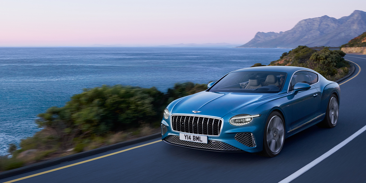 Bentley Budapest New Bentley Continental GT Azure coupe in Light Windsor blue paint with 22 inch Azure wheels and chrome grill, driving dynamically by the sea