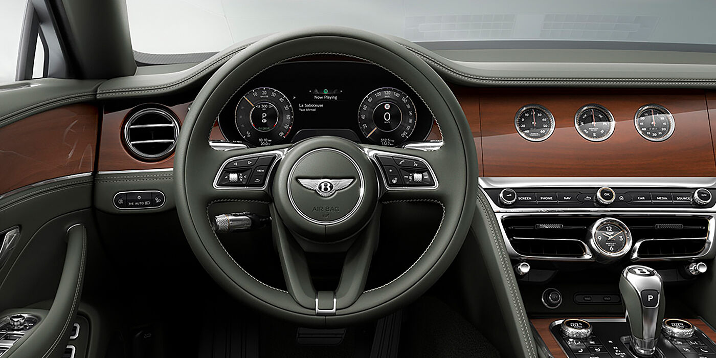 Bentley Budapest New Bentley Flying Spur sedan front cabin in Cumbrian Green hide and Crown Cut walnut veneer showing steering wheel and Rotating Display with three clocks on face