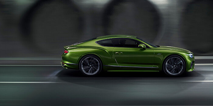  Bentley Budapest Bentley Continental GT coupe in Tourmaline Green paint driving in profile on a dark road