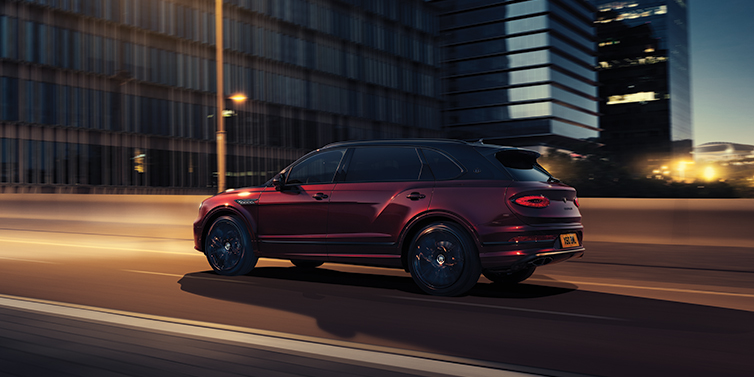 Bentley Budapest Bentley Bentayga Extended Wheelbase Mulliner SUV in Cricket Ball red paint driving dynamically in city at night